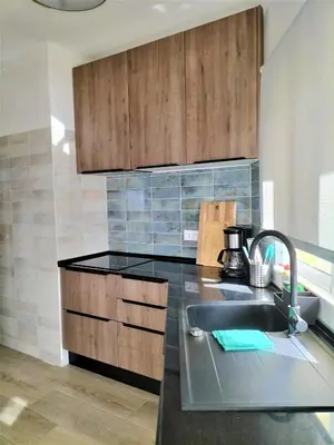 a kitchen with a sink and wooden cabinets at T2 Requinte e Vista Mar 4 pax in Quarteira