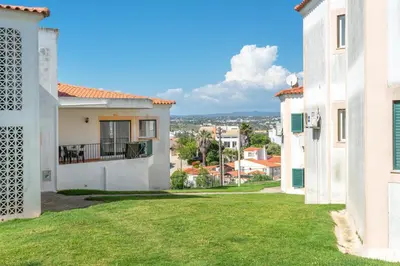 a table with an umbrella in the grass at BnB Homes Large fully equipped Apartment with 2 bedrooms, swimming pool & patio in Albufeira