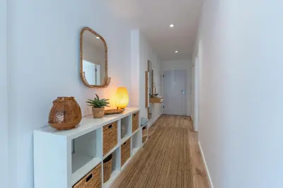 a hallway with a mirror and a table with a lamp at Stunning 3 BDR Flat W/ Rooftop Pool by LovelyStay in Albufeira