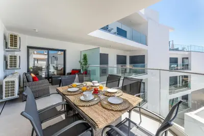 a dining room and living room with a table and chairs at Stunning 3 BDR Flat W/ Rooftop Pool by LovelyStay in Albufeira