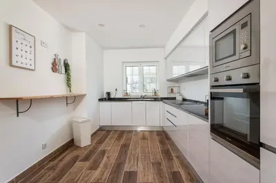 a kitchen with white cabinets and wood floors and a stove at Privilege Casa dos Capuchinhos, in the heart of Faro in Faro