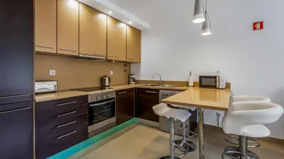 a kitchen with wooden cabinets and a table with stools at Luminous 2 BDR Apartment W/Pool by LovelyStay in Albufeira