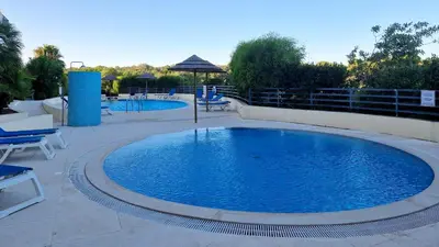 a large blue pool with chairs and an umbrella at Albufeira Oasis Retreat in Albufeira