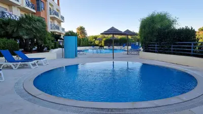 a large blue pool with chairs and an umbrella at Albufeira Oasis Retreat in Albufeira