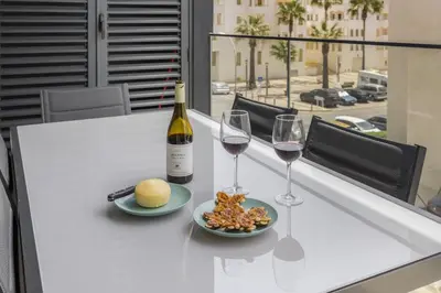 a table with two glasses of wine and a plate of food at Terracos de Quarteira II Navy by Real Properties in Quarteira