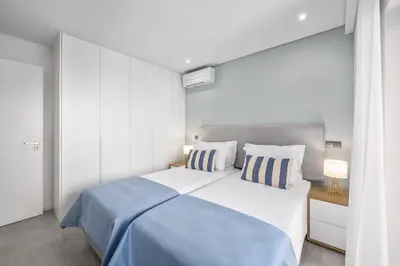 a bedroom with a large bed with blue sheets and pillows at Terracos de Quarteira II Navy by Real Properties in Quarteira