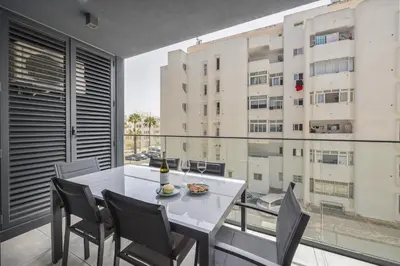 a dining room with a table and chairs and a large window at Terracos de Quarteira II Navy by Real Properties in Quarteira