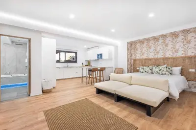 a bedroom with a bed and a couch and a kitchen at Casa Chameleon in Almancil