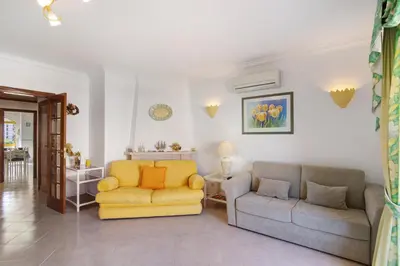 a living room with a yellow chair and a couch at Vila Mar Azul in Quarteira