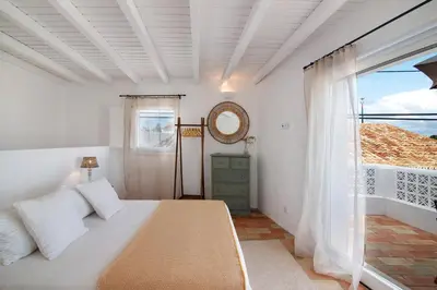 a white bedroom with a bed and a mirror at Casa de Benafim 51 in Benafim