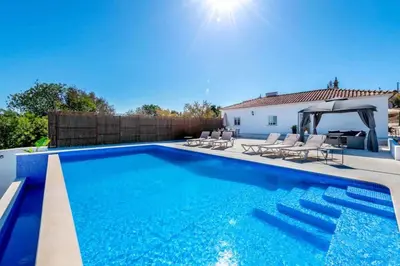 a swimming pool with chairs and a house at Casa Emella Luxury Villa Albufeira in Albufeira