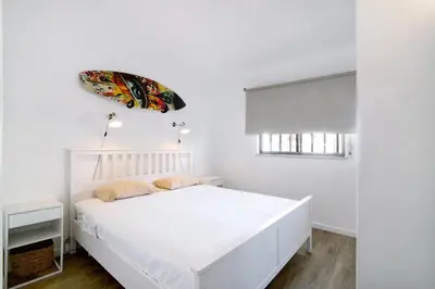a white bedroom with a white bed and a window at Blue wave escape apartment -T1 perto da praia com varanda in Albufeira