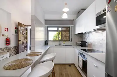 a kitchen with white cabinets and a table and chairs at Blue wave escape apartment -T1 perto da praia com varanda in Albufeira