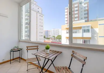 a balcony with a wooden table and two benches at Sea-Front 1' Min! - Apartment with AC & WiFi in Quarteira