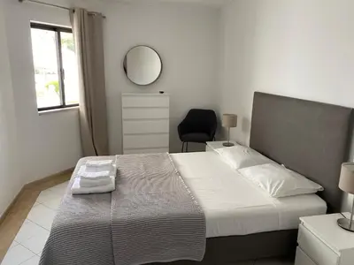 a bedroom with a bed with a mirror and a chair at Casa Porto Marina in Vilamoura