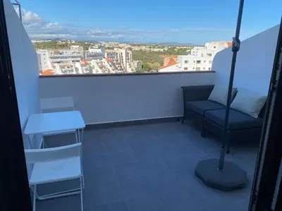 a balcony with a chair and a table and a window at CASA Vila Magna T0 in Albufeira