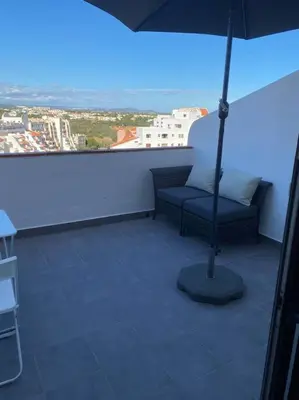 a chair and an umbrella in a room with a window at CASA Vila Magna T0 in Albufeira