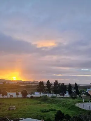a sunset over a field with trees and a river at Sleep and Fly in Faro