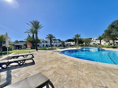 a swimming pool in a resort with benches and palm trees at Albufeira Balaia Golf Vilage 3 With Pool by Homing in Albufeira