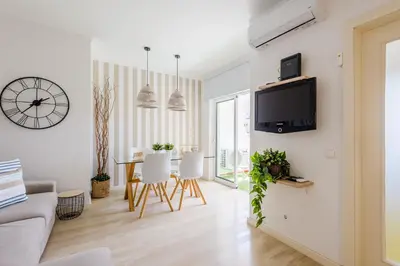 a living room with a table and a tv on a wall at Alfamar Apartment at Praia da Falesia in Albufeira