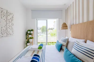 a bedroom with a bed with blue and white pillows at Alfamar Apartment at Praia da Falesia in Albufeira