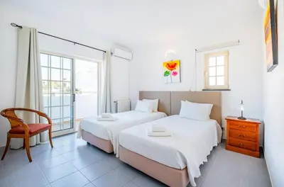 two beds in a room with a chair and a window at Villa Nina in Albufeira