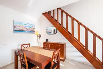 a dining room with a wooden table and a staircase at Sweet Home Arrifes in Albufeira