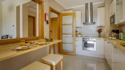a kitchen with white cabinets and a counter with a sink at Greice Homes- 3 bed Luxury Apartment in Vilamoura in Quarteira