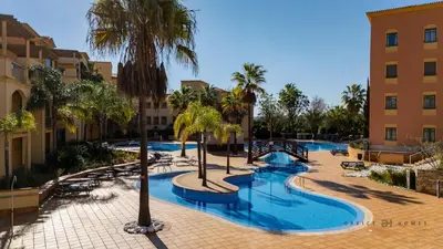 a swimming pool with palm trees in a resort at Greice Homes- 3 bed Luxury Apartment in Vilamoura in Quarteira