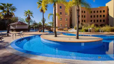 a swimming pool with palm trees and a building at Greice Homes- 3 bed Luxury Apartment in Vilamoura in Quarteira