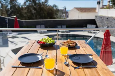 a wooden table with a bowl of fruit and glasses of orange juice at Malpique heated pool & Jacuzzi Guest House in Albufeira