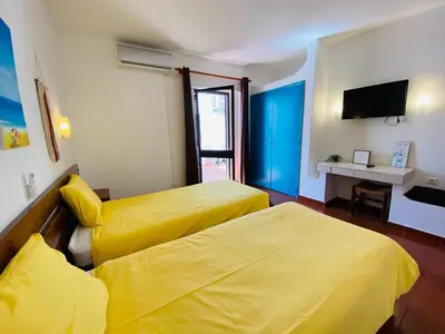 a hotel room with two beds and a television at Casa da Oura in Albufeira