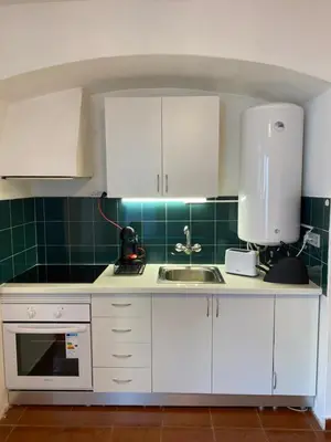 a kitchen with white cabinets and a sink and green tiles at Casa da Oura in Albufeira