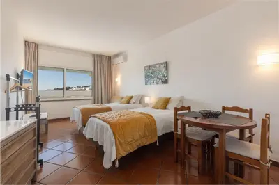 a hotel room with two beds and a table at Apartamentos Pescadores in Albufeira