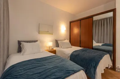 a hotel room with two beds and a mirror at Apartamentos Pescadores in Albufeira
