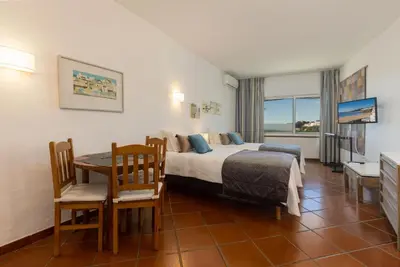 a hotel room with a bed and a table and chairs at Apartamentos Pescadores in Albufeira