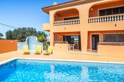 a villa with a swimming pool in front of a house at Casa Pluma in Albufeira