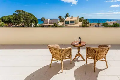 a table and chairs on a patio with a view of the ocean at Villa Luz Figueiras in Galé