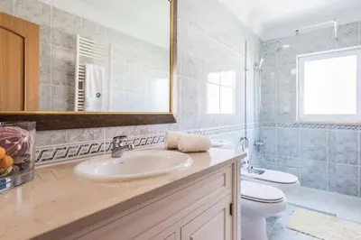 a bathroom with a sink and a toilet and a mirror at Villa Luz Figueiras in Galé
