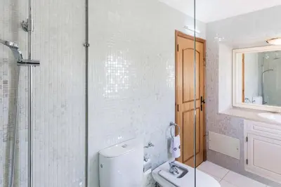a bathroom with a toilet and a glass shower at Villa Luz Figueiras in Galé