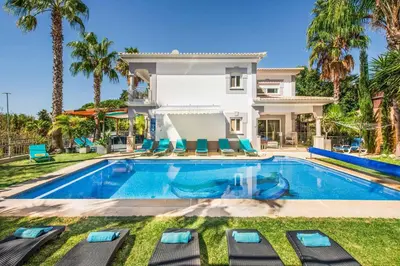 a villa with a swimming pool and palm trees at Villa Paris in Terras Novas