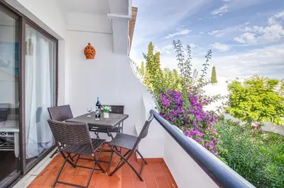 a balcony with a table and chairs and flowers at Seaside Retreat with Pool, AC, and Fast Wi-Fi in Albufeira