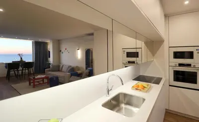 a kitchen with a sink and a living room at Blue over blue in Quarteira