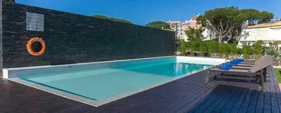 a swimming pool with a bench next to a brick wall at Villa | w/ Private Pool, Tennis Courts & Golf Putt in Vilamoura