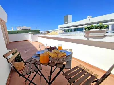 a table with a basket of fruit and drinks on a balcony at Lovely Terrace Studio Baixa Faro in Faro