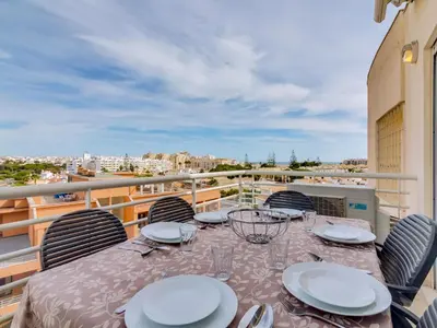 a table on a balcony with a view of a city at AL - Apartamento Moura Praia in Vilamoura