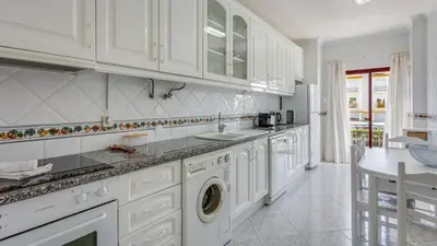 a white kitchen with a washer and dryer at Serene Apartment W/ Balcony and Pool by LovelyStay in Quarteira