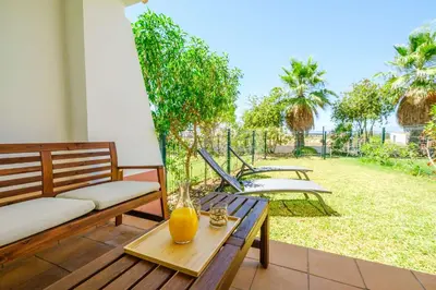 a patio with benches and a table with a view of a yard at Villa Baya - Great family complex with communal pool in Albufeira