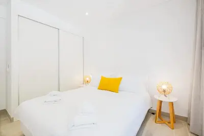 a white bedroom with a white bed and a yellow pillow at Apartment Tanta - located at the gates of the old in Albufeira