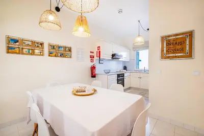a patio with a white table and chairs and a pergola at Apartment Vento in Albufeira